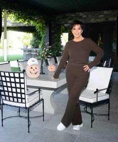 a woman standing in front of a table with two chairs and a pumpkin on it