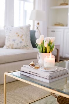 a living room with a couch, coffee table and flowers on top of the book