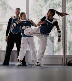 two people are practicing martial moves in front of a group of other people on the floor