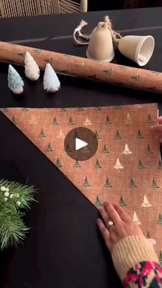 someone is making a paper christmas tree ornament on a piece of wood with pine cones