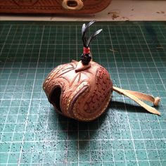 an old baseball ball with feathers on it sitting on a green counter top next to a pair of scissors