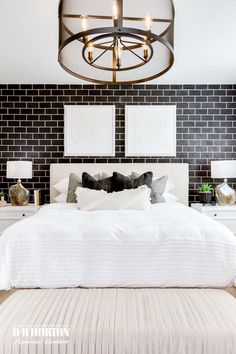 a white bed sitting under a chandelier in a bedroom