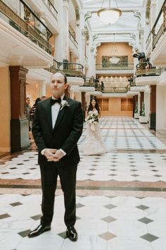 a man in a tuxedo standing on a tiled floor