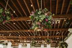 hanging flower baskets in the middle of a banquet hall filled with flowers and greenery