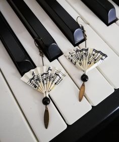 the keys of a piano are decorated with small fan shaped pins and black beads on them