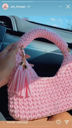 a pink purse is being held up in the air by someone's hand while driving