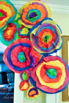 colorful paper flowers are hanging on the wall