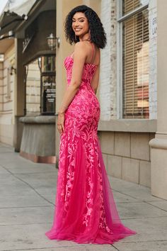 a woman in a pink dress standing on the sidewalk