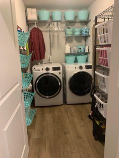 a washer and dryer sitting in a room next to each other with baskets on the wall