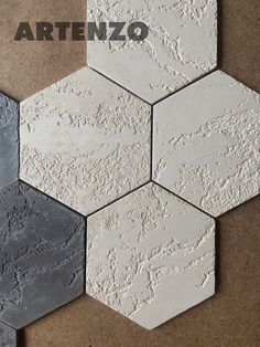 some white and grey hexagonal tiles on a brown surface with the words arteno written