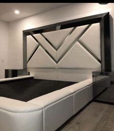 a white bed with black sheets and headboard in a room that has wood floors