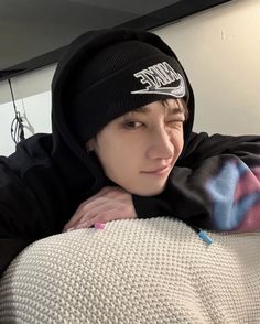 a young man wearing a black nike beanie on top of a couch in a room