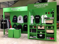 the madstore store has green walls and shelves with t - shirts on them