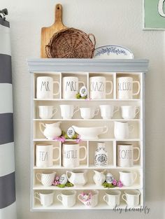 a shelf filled with cups and saucers on top of a wall