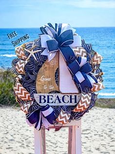 a wooden sign on the beach that says welcome to the beach and is decorated with ribbons