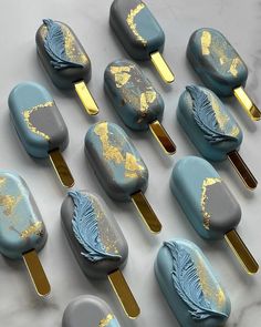 some ice cream pops with gold leaf designs on them and blue frosted lollipops