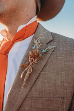 a close up of a person wearing a suit and an orange tie with a boutonniere