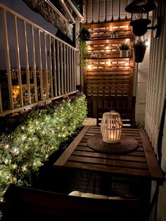 a wooden table topped with a lit lantern on top of a balcony next to trees