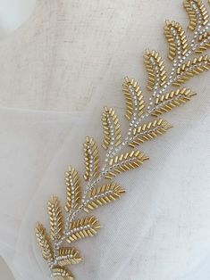 a gold and white bridal sash with leaves on it