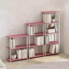 a pink shelf with books on it in a room next to a white wall and rug