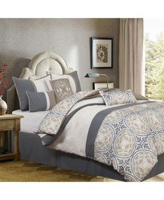 a bedroom with a large bed covered in gray and white comforter sets next to a window