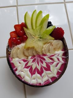 a bowl filled with fruit on top of a white tile floor next to a tiled wall