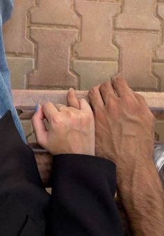 two people are sitting on a bench with their hands touching each other's fingers