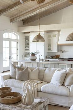 a living room filled with white furniture and lots of pillows on top of it's couch