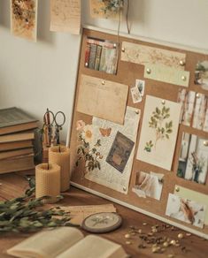 a cork board covered in pictures and papers on top of a wooden table next to candles