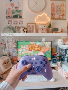 a person holding a purple controller in front of a computer desk with a clock on the wall