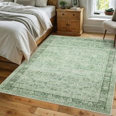 a large green rug in a bedroom next to a bed