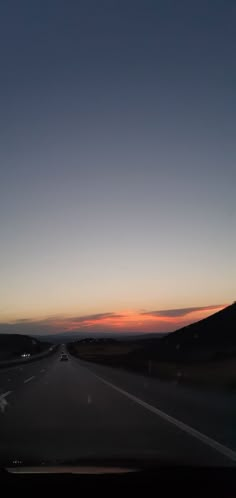 the sun is setting on an empty highway