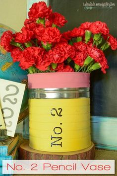 red carnations in a yellow tin can with the words no 2 pencil vase