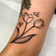 a black and white photo of a flower tattoo on the right leg with bees flying around it