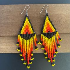 a pair of colorful beaded earrings on top of a wooden table