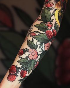 a woman's arm with flowers and leaves on it