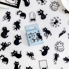 black and white cat stickers are on a table next to a plate with food