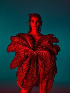 a woman is standing in front of a blue background with red lines on her body