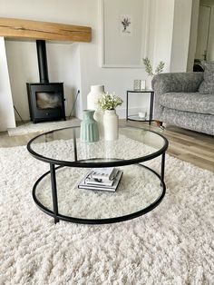 a living room with a couch, coffee table and fireplace in the background on a shaggy rug