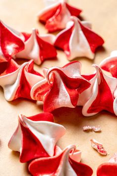 some red and white flowers are on a table with other petals in the middle of it