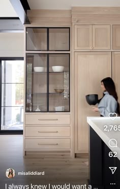 a woman standing in front of a kitchen counter next to a sink and cupboards