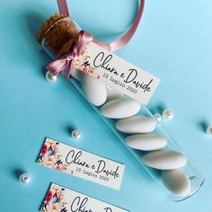 wedding favors with name tags on them sitting in a glass tube next to some pearls