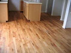 an empty kitchen with wooden floors and cabinets