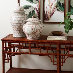 two vases sitting on top of a wooden table next to a mirror and potted plant