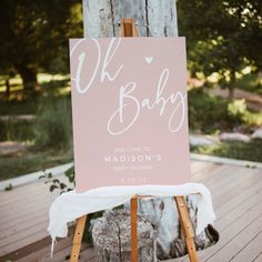 a welcome sign for a baby is displayed on a wooden easel in front of a tree