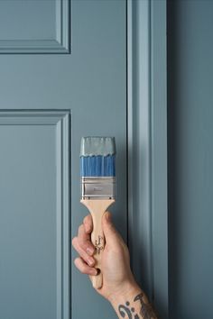 a person holding a paintbrush in their hand near a blue door with the word fix painted on it