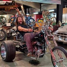 a man riding on the back of a motorcycle in a garage next to other motorcycles