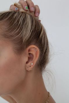 a woman with her hair in a bun wearing gold ear cuffs and a diamond necklace