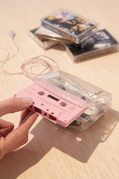 a person is holding a pink cassette tape in their hand and pressing it to the side