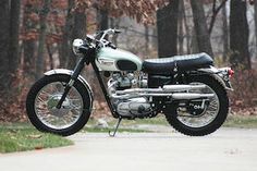 a motorcycle parked on the side of a road in front of some trees and grass